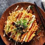 Ízletes okonomiyaki palacsinta, majonézzel és zöldhagymával díszítve.