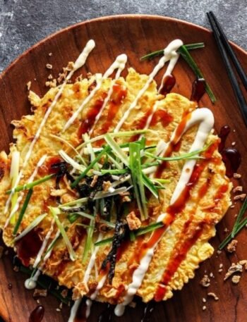 Ízletes okonomiyaki palacsinta, majonézzel és zöldhagymával díszítve.