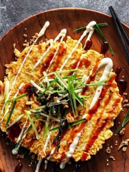 Ízletes okonomiyaki palacsinta, majonézzel és zöldhagymával díszítve.