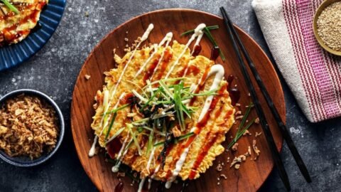 Ízletes okonomiyaki palacsinta, majonézzel és zöldhagymával díszítve.