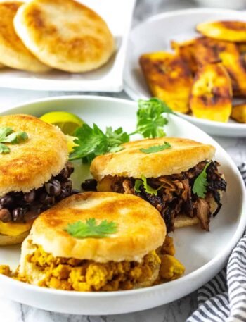 Három arepa különböző töltelékekkel: fekete bab, húsgulyás és tojásos. Korianderrel díszítve.