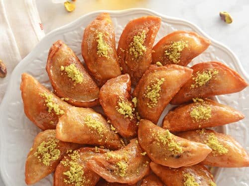 Sült, pisztáciával szórta palacsinták egy fehér tányéron.